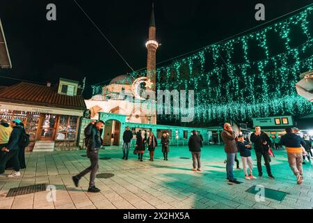 14 mars 2024, Sarajevo, Bosnie-Herzégovine : minaret illuminé des mosquées de Bascarsija projette une lueur captivante sur la ville historique, refl Banque D'Images