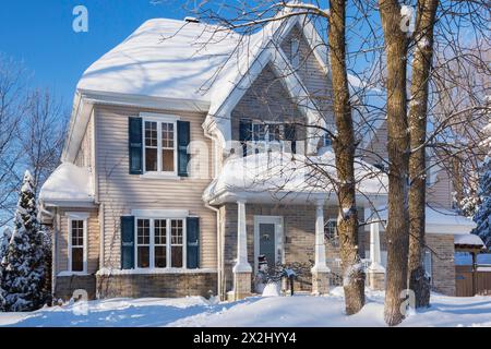 Façade de maison de style cottage en brique bronzée et vinyle avec garniture bleue en hiver, Québec, Canada Banque D'Images