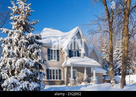 Façade de maison de style cottage en brique bronzée et vinyle avec garniture bleue en hiver, Québec, Canada Banque D'Images