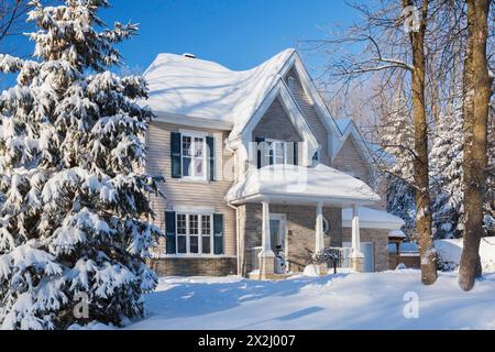 Façade de maison de style cottage en brique bronzée et vinyle avec garniture bleue en hiver, Québec, Canada Banque D'Images