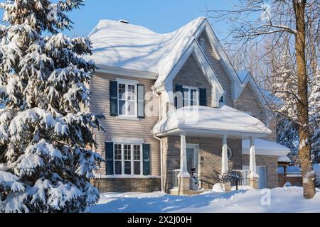 Façade de maison de style cottage en brique bronzée et vinyle avec garniture bleue en hiver, Québec, Canada Banque D'Images