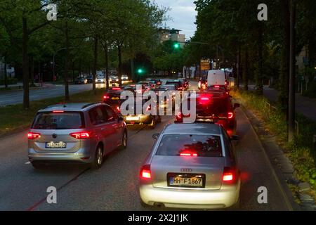 Hambourg, Allemagne - 19 mai 2023 : les véhicules s'alignent à un feu de circulation dans une rue de la ville pendant le crépuscule, avec la lueur des feux arrière rouges et la lâche de rue Banque D'Images