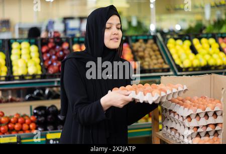 Fille asiatique dans le hijab achète des œufs de poule dans le supermarché Banque D'Images