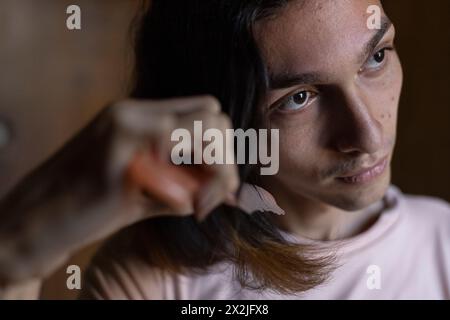 Jeune homme transgenre (22) se peignant les cheveux, photographié d'en haut Banque D'Images