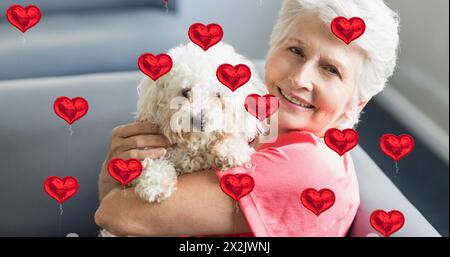 Image d'icônes de coeur au-dessus d'une femme âgée souriante tenant le chien Banque D'Images