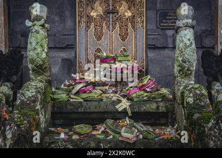 Une exposition de balinais traditionnels colorés offrant des paniers en matériaux naturels, placés à l'entrée d'un temple avec des sculptures complexes. Banque D'Images