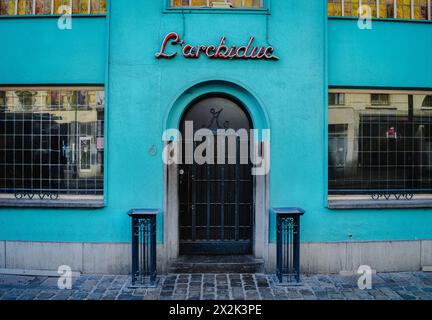 Cette image capture un bâtiment turquoise lumineux avec un signe de néon rétro distinctif et une porte arquée classique, reflétant l'architecture urbaine unique Banque D'Images