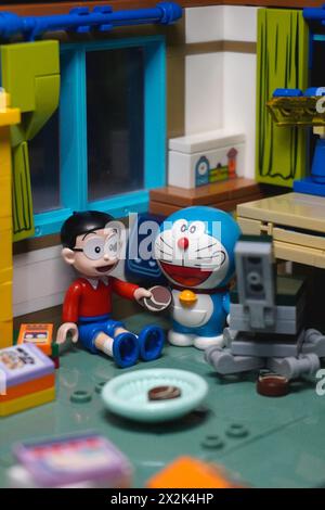 Figurines de jouets japonaises (Nobita et Doraemon) assis et mangeant un gâteau au chocolat ensemble Banque D'Images