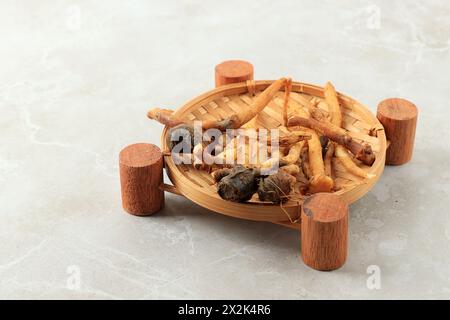 Doigt racine Temu KUNCI dans la plaque de bambou sur la table de fond gris Banque D'Images