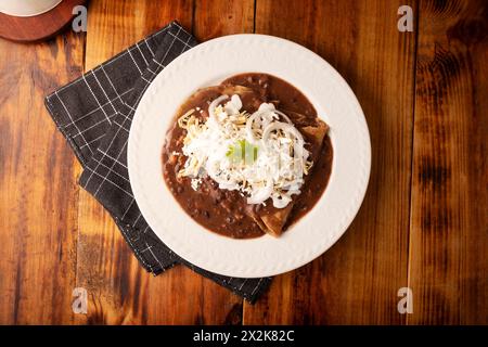 Enfrijoladas. Tortillas de maïs trempées dans de la sauce aux haricots, recouvertes de crème et de fromage, elles peuvent être recouvertes ou fourrées de viande de poulet, de fromage ou d'avoine Banque D'Images