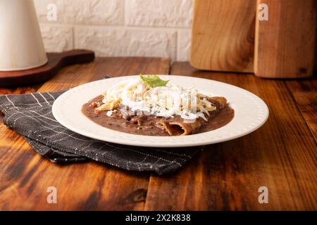 Enfrijoladas. Tortillas de maïs trempées dans de la sauce aux haricots, recouvertes de crème et de fromage, elles peuvent être recouvertes ou fourrées de viande de poulet, de fromage ou d'avoine Banque D'Images