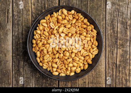 Arachides grillées salées sur assiette sur une table en bois. Vue de dessus. Banque D'Images