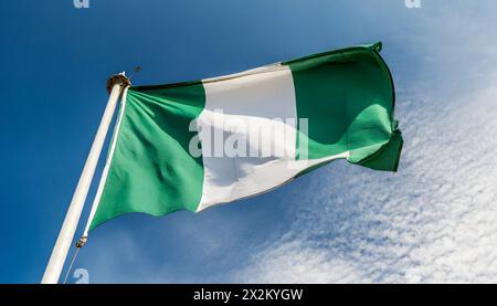 Die Fahne von Nigeria flattert im Wind, isoliert gegen blauer Himmel Banque D'Images