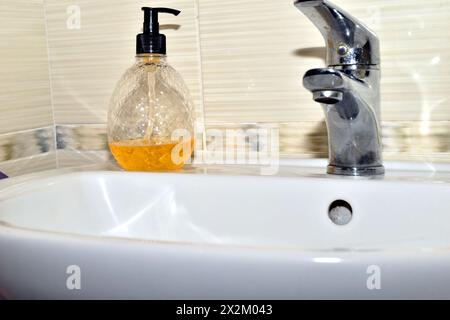 Sur le lavabo de la salle de bain, il y a une bouteille de savon liquide jaune. Banque D'Images