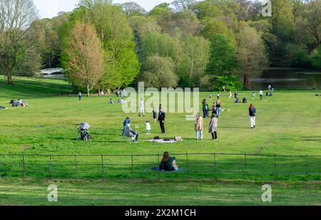 Londres. UK- 04.14.2023. Foule de personnes se relaxant et profitant d'une journée sur le terrain d'herbe verte d'un parc sur une belle journée chaude et ensoleillée de printemps. Banque D'Images