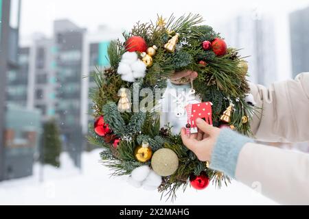 Personne tenant la couronne de Noël avec des décorations Banque D'Images