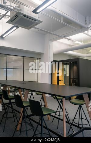 Un espace de bureau élégant et contemporain, avec une longue table de conférence avec des chaises élégantes et un design minimaliste sous un éclairage lumineux Banque D'Images
