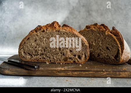 Une miche de pain au levain de seigle maison fraîchement tranchée est posée sur une planche à découper en bois rustique, mettant en valeur sa texture aérée et sa croûte Banque D'Images