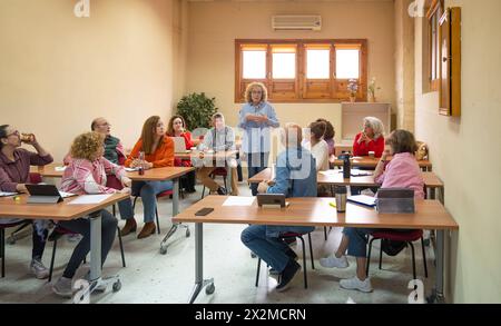 Adultes seniors participant attentivement à une classe d'apprentissage tout au long de la vie avec une instructrice menant la discussion Banque D'Images