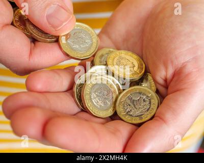 Gros plan des mains comptant l'argent comptant dans les pièces de 1 livre du Royaume-Uni Banque D'Images