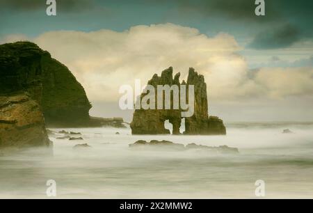 Coucher de soleil dans les tons dorés et bleus entre les rochers de la plage de Portizuelo, sur la côte asturienne, Espagne Banque D'Images