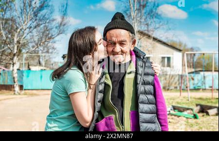 Portrait de petite-fille embrassant dans la joue son grand-père de 75 ans dans un village russe Banque D'Images