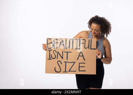 Biracial jeune femme plus modèle de taille tient l'affiche sur un fond blanc Banque D'Images