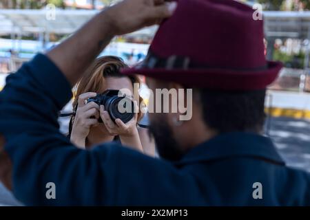 Jeune femme latino-américaine avec appareil photo à la main prend des photos de son partenaire en vacances. Concept de marche et de vacances Banque D'Images