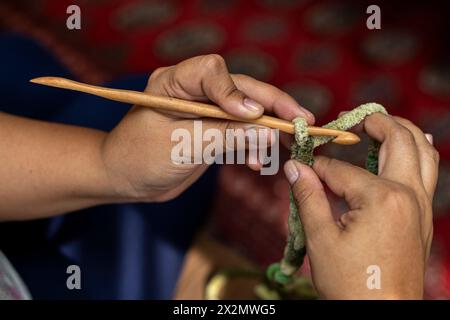 Gros plan des mains d'une femme tenant une aiguille au crochet en bambou Banque D'Images