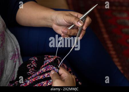 Gros plan des mains d'une femme latino-américaine tenant un type d'aiguilles circulaires idéales pour tricoter de longues longueurs dans le rond avec des fils de laine, Con Banque D'Images