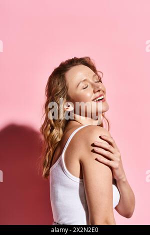 Une femme sereine avec les yeux fermés debout devant un mur rose vif, exsudant la beauté naturelle et le calme intérieur. Banque D'Images