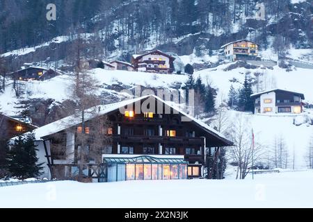 Plusieurs petites maisons dans les montagnes boisées le soir d'hiver. Banque D'Images