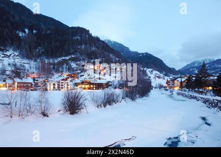 Rivière couverte de glace et plusieurs petits hôtels dans les montagnes le soir d'hiver. Banque D'Images