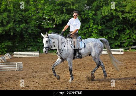 Jockey dans des lunettes monte à cheval près de la barrière sur l'hippodrome Banque D'Images