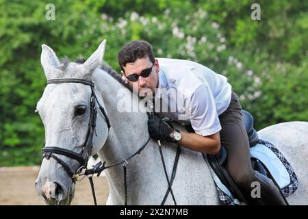 Jockey dans des verres avec cheval fouet câlin sur l'hippodrome Banque D'Images