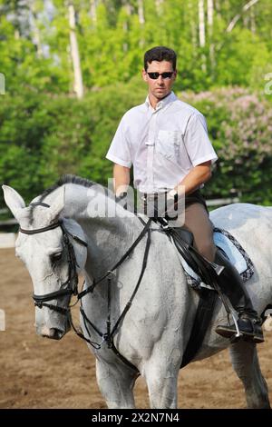 Jockey dans le siège de lunettes sur le cheval sur l'hippodrome Banque D'Images