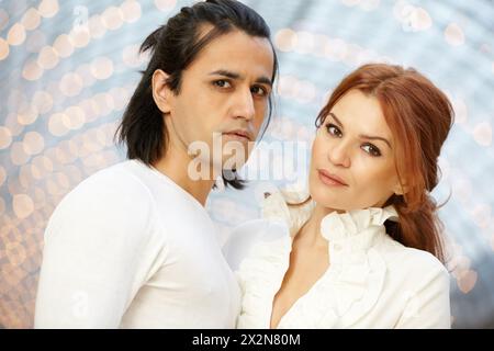 Homme aux cheveux foncés et femme aux cheveux roux se tiennent côte à côte et regardent devant Banque D'Images