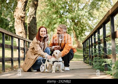 Un couple aimant est assis sur un pont avec leurs deux chiens, profitant d'un moment paisible dans le parc. Banque D'Images