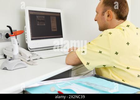 Dentiste regarde attentivement les rayons X de mâchoire à l'écran d'ordinateur dans la clinique dentaire. Banque D'Images