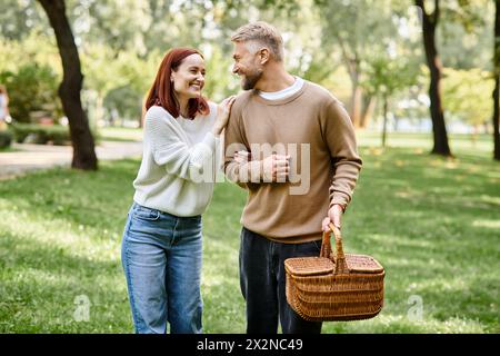 Couple adulte en tenue décontractée marchant dans le parc tenant un panier. Banque D'Images