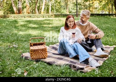 Un homme et une femme sont assis sur une couverture dans l'herbe, profitant d'une journée paisible dans le parc. Banque D'Images