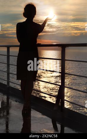 silhouette sombre de femme tenant le soleil et debout sur le pont au coucher du soleil Banque D'Images