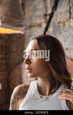 Une jeune femme avec des tatouages de manche regarde au loin. Jeune femme avec des tatouages regardant soigneusement dans un cadre rustique Banque D'Images