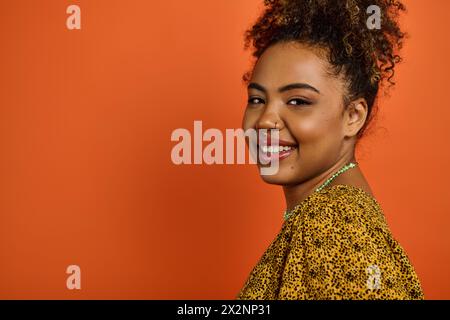 Femme afro-américaine en tenue élégante souriant chaleureusement à la caméra. Banque D'Images