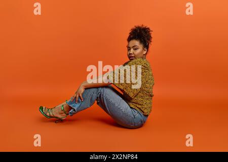Femme afro-américaine élégante assise, jambes croisées, fond vibrant. Banque D'Images