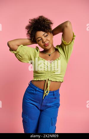 Femme afro-américaine en tenue élégante pose avec les mains sur la tête. Banque D'Images