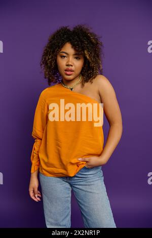 Femme afro-américaine élégante pose gracieusement dans le haut orange vibrant. Banque D'Images