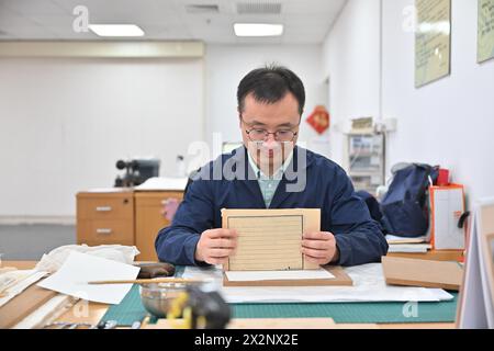 (240423) -- TIANJIN, 23 avril 2024 (Xinhua) -- Gao Xuemiao lie un livre ancien restauré à la bibliothèque de Tianjin dans la municipalité de Tianjin, au nord de la Chine, 22 avril 2024. La bibliothèque de Tianjin abrite une collection de 590 000 livres anciens et a mené des travaux de restauration de livres anciens pendant plus de 70 ans. Gao Xuemiao, 38 ans, dirige l’équipe de restauration de la bibliothèque. Il est le premier expert en restauration ayant une formation en chimie depuis la création du département en 1978. De nos jours, la restauration de livres anciens est de plus en plus considérée comme un processus interdisciplinaire. L'incorporation du produit chimique a Banque D'Images