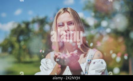 Une fille souffle des confettis en papier multicolores de ses mains. Banque D'Images