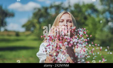 Une fille souffle des confettis en papier multicolores de ses mains. Banque D'Images